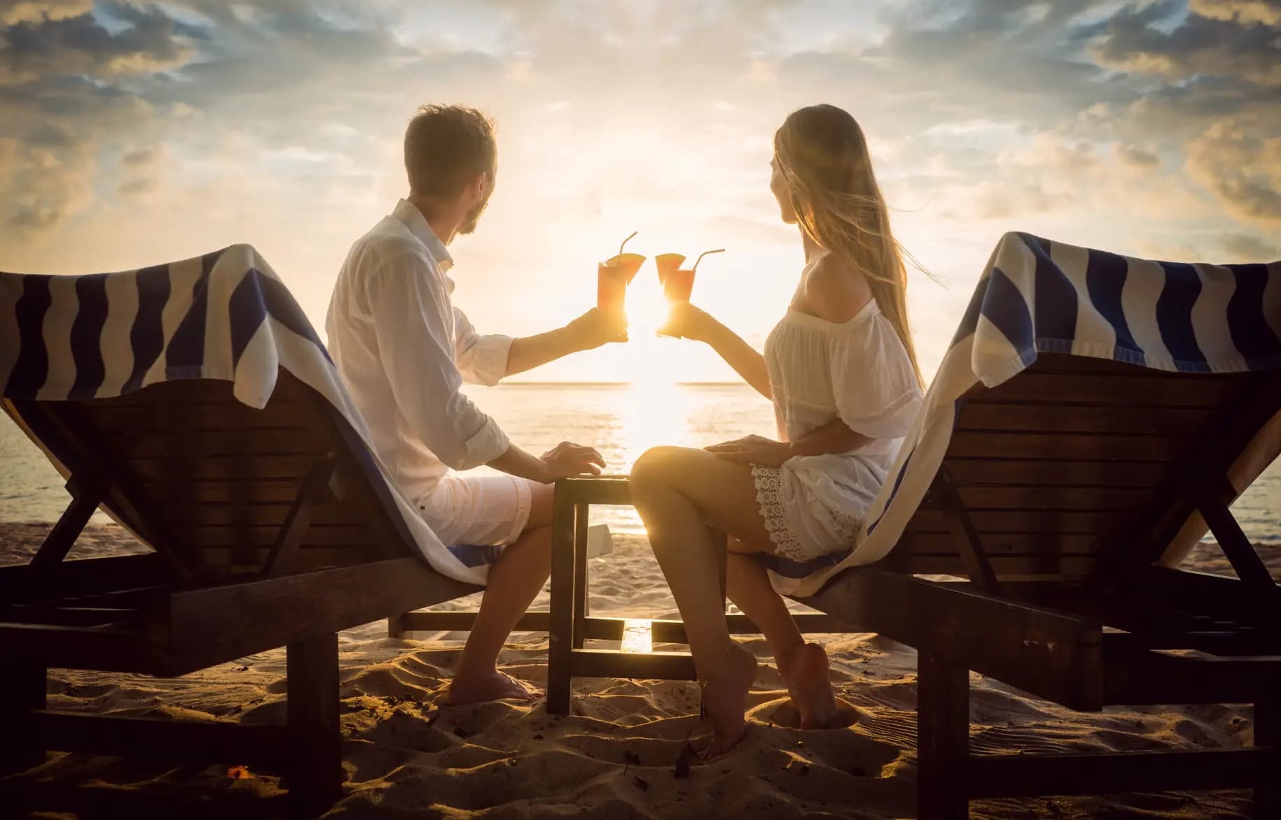 Young-couple-sitting-on-a-beach-at-sunset-smiling-and-relaxing-by-achieving-FIRE