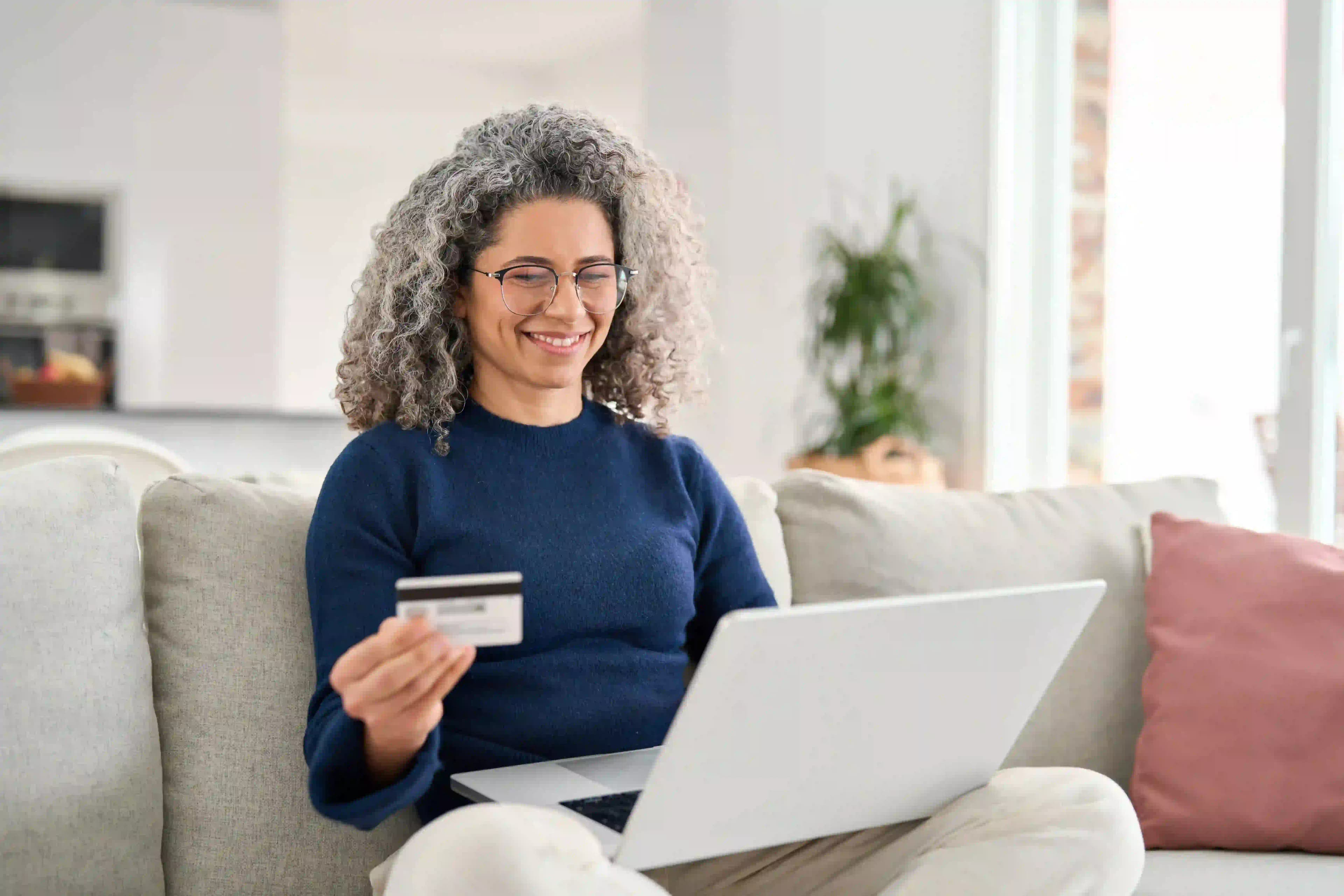 person-holding-a-credit-card-while-shopping-on-their-laptop-in-canada