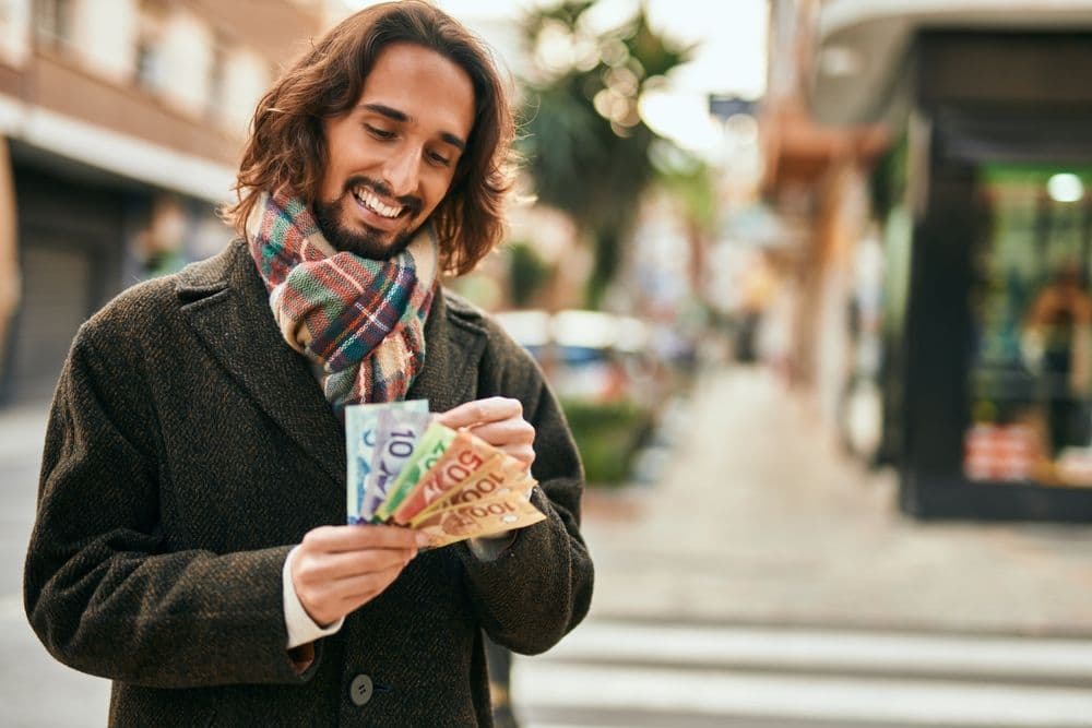 man-smiling-while-holding-money-in-his-hands