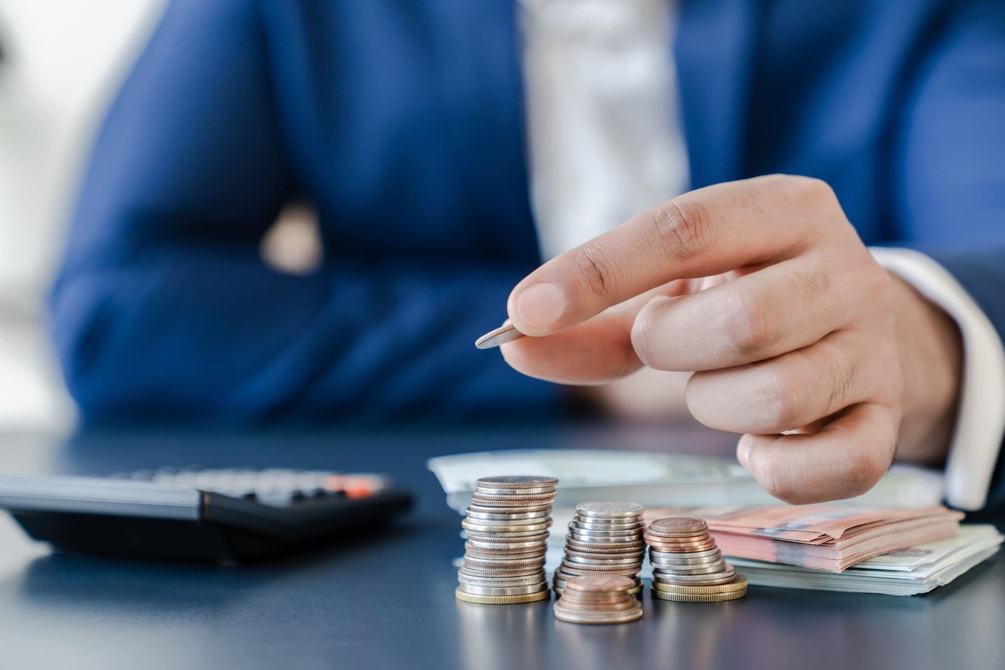 man-in-blue-suit-counting-his-cash-with-a-calculator