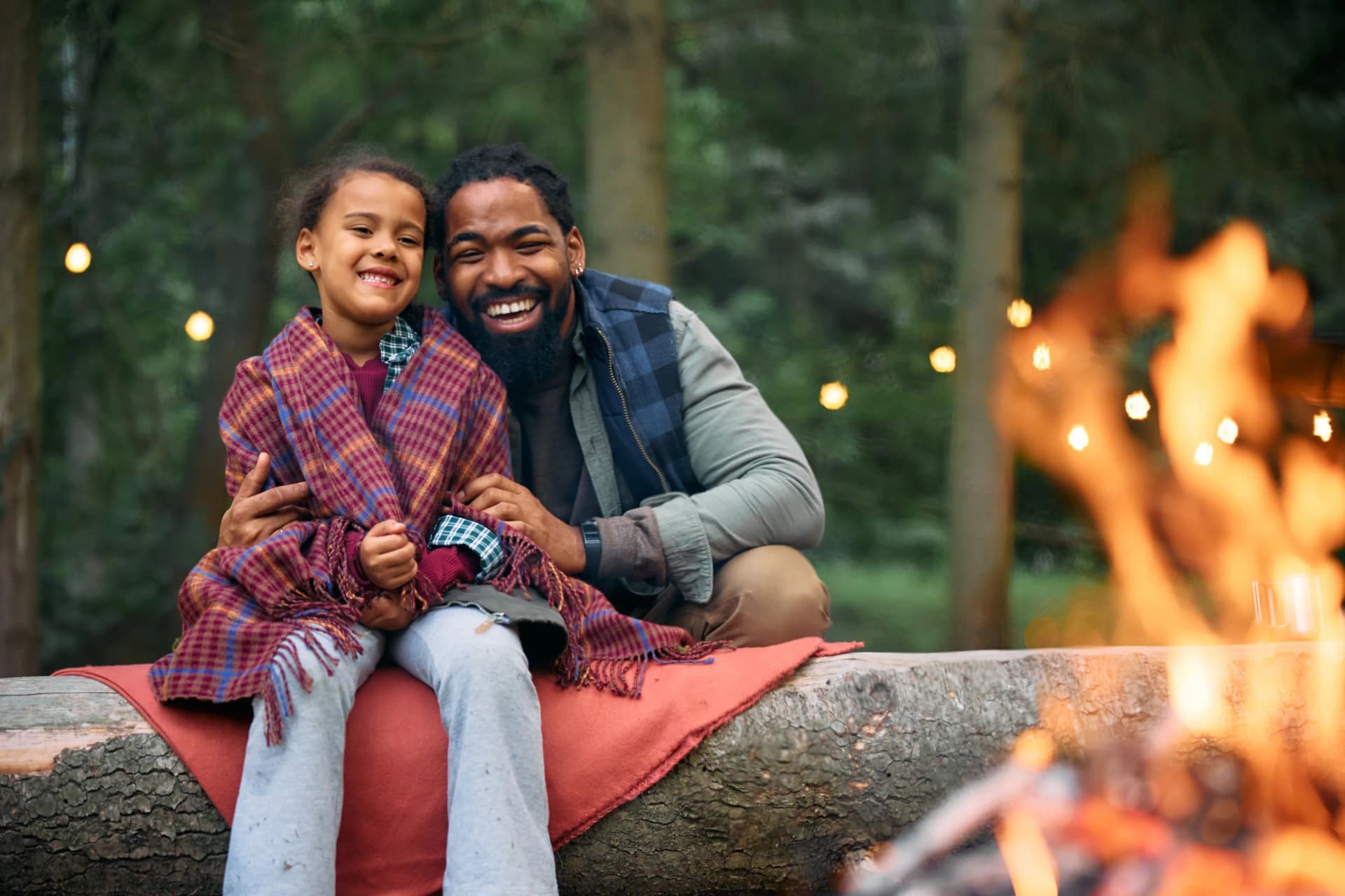 Happy father and daughter enjoying a bonfire while camping in woods Happy father and daughter enjoying a bonfire while camping in woods