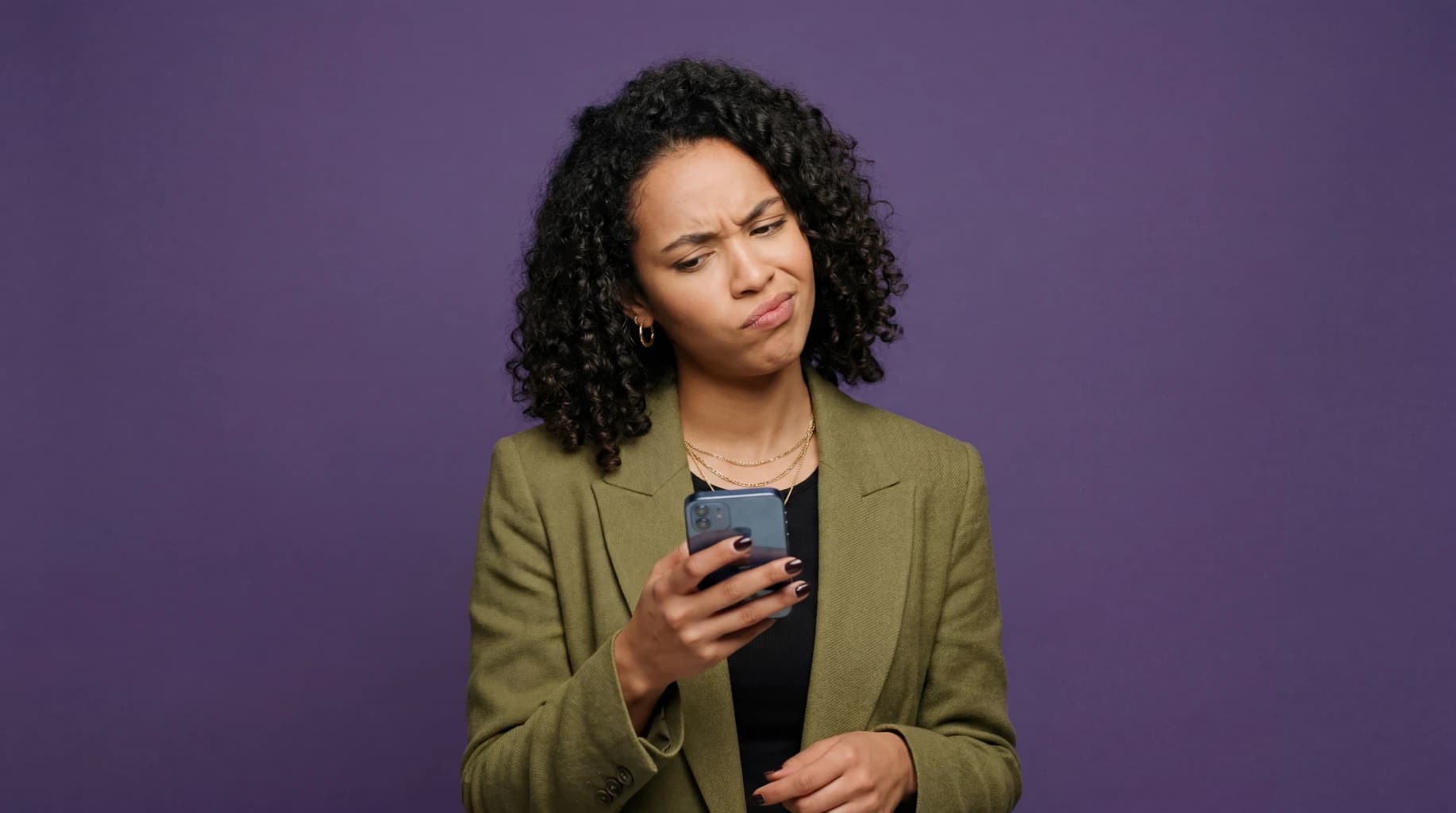 Young woman showing confused reaction while looking at mobile phone