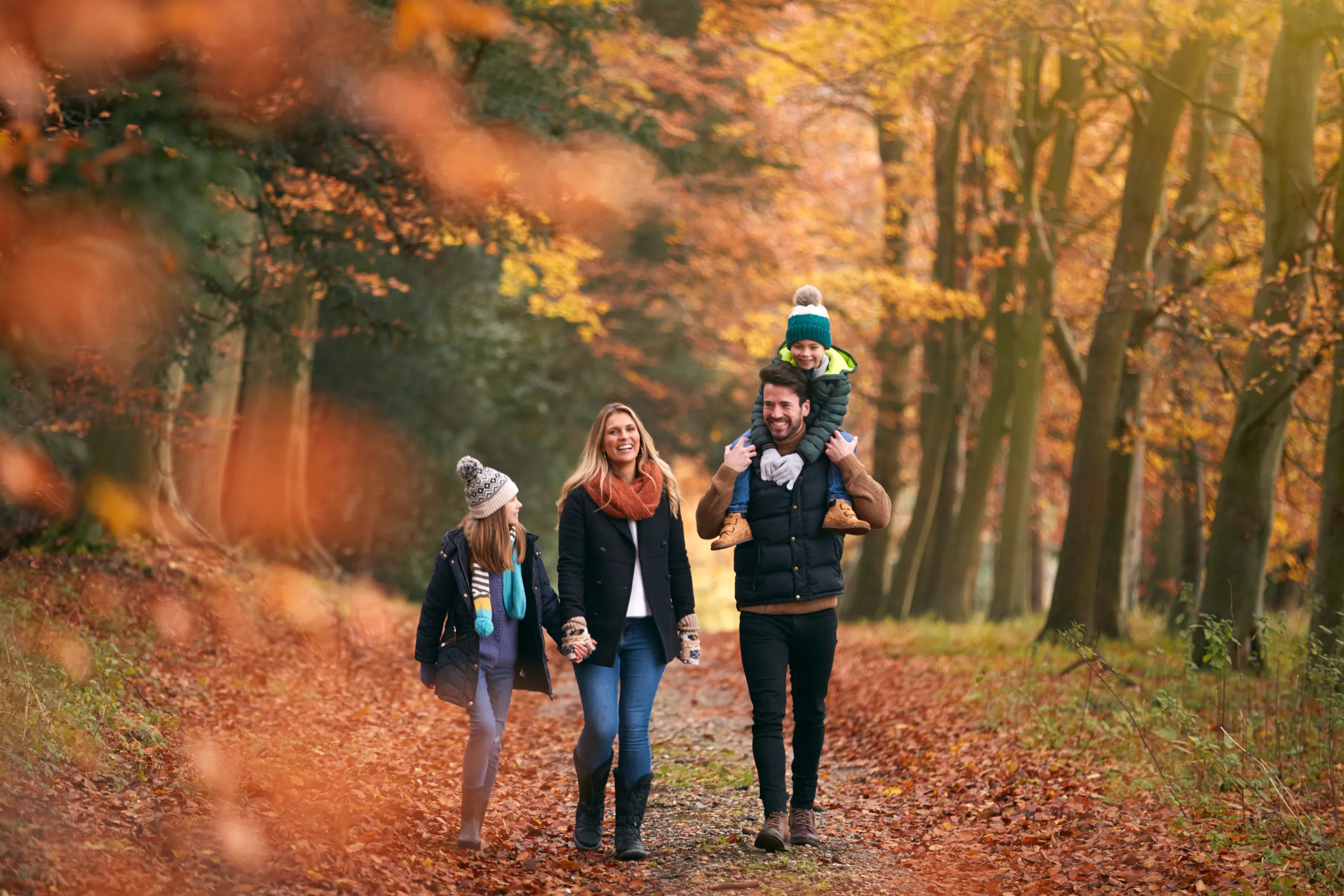 Family Walking Along Autumn Woodland Path
