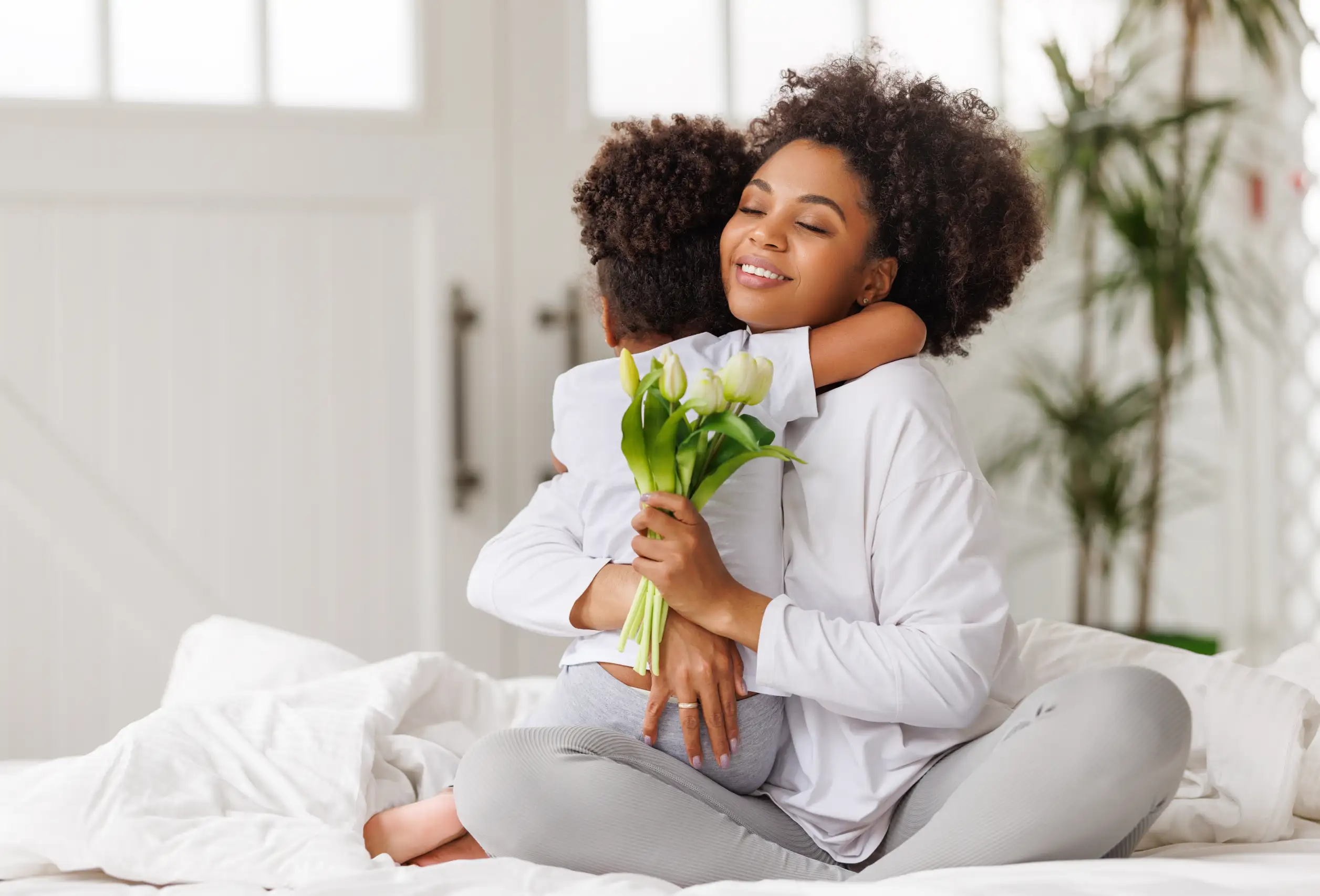 mother-holding-flowers-while-hugging-young-daughter