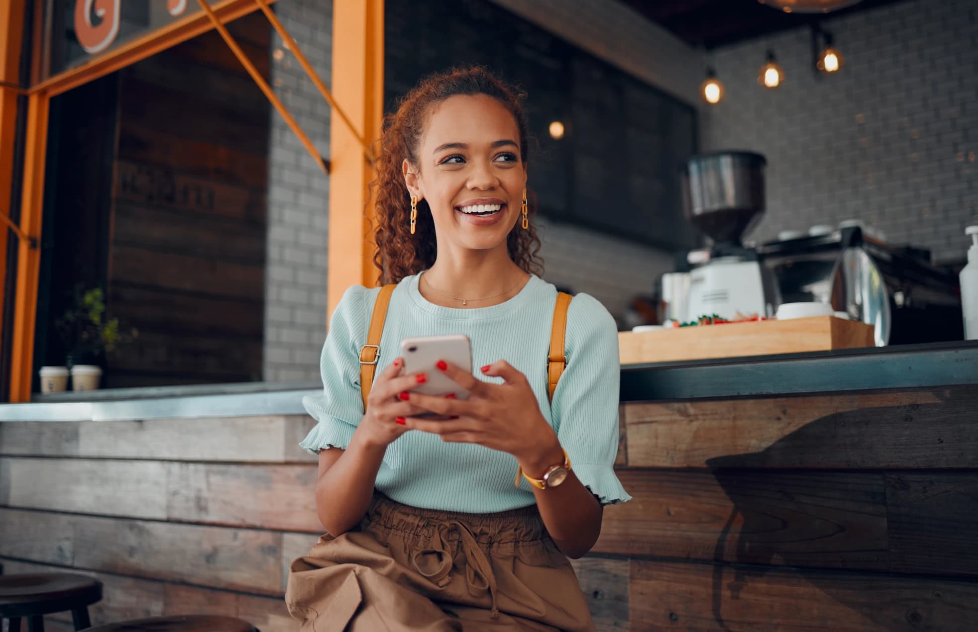 Woman holding phone thinking at a coffee shop