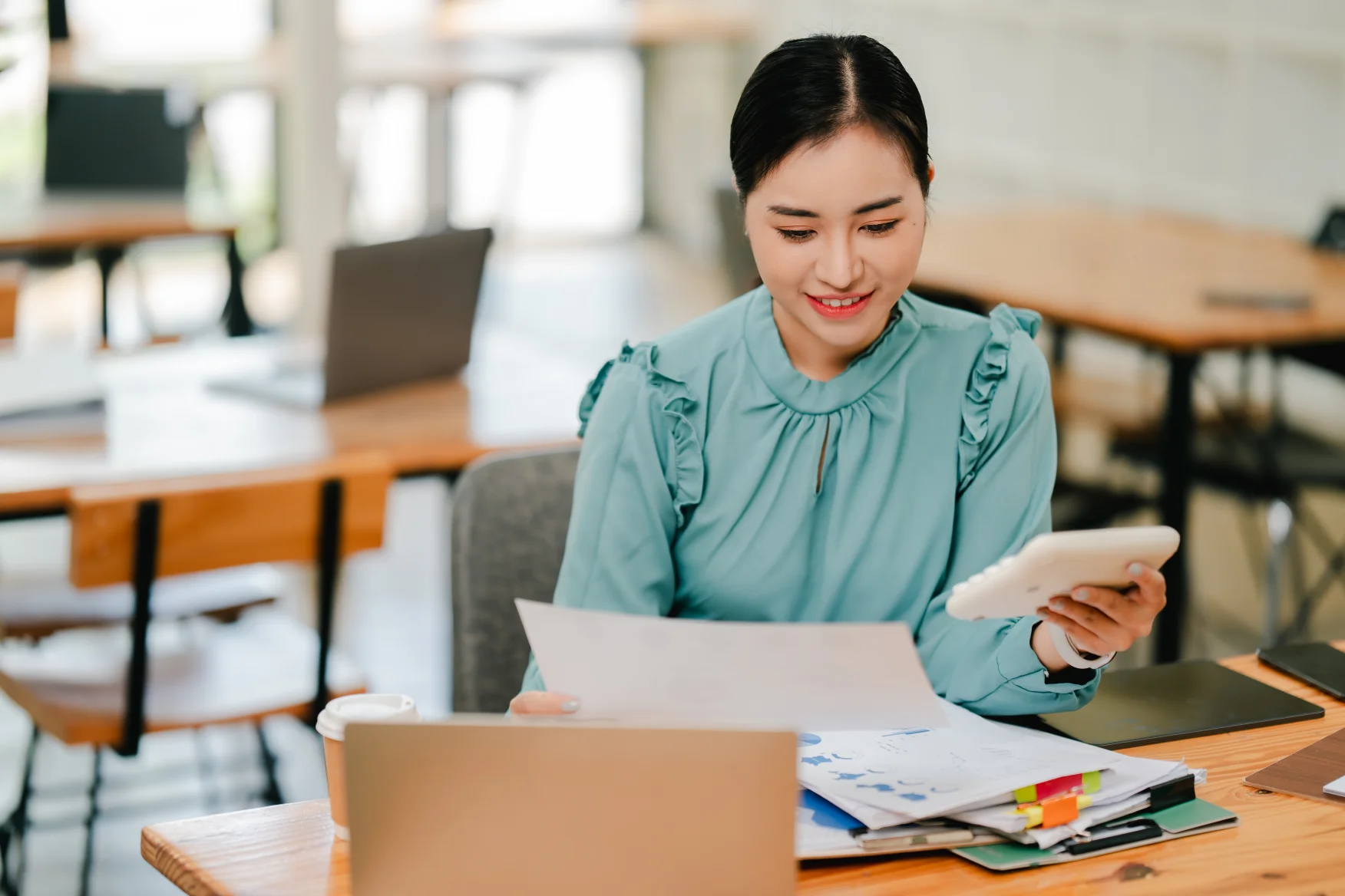 person-confidently-organizing-tax-documents-with-calculator-and-laptop-smiling-while-filing-canadian-taxes