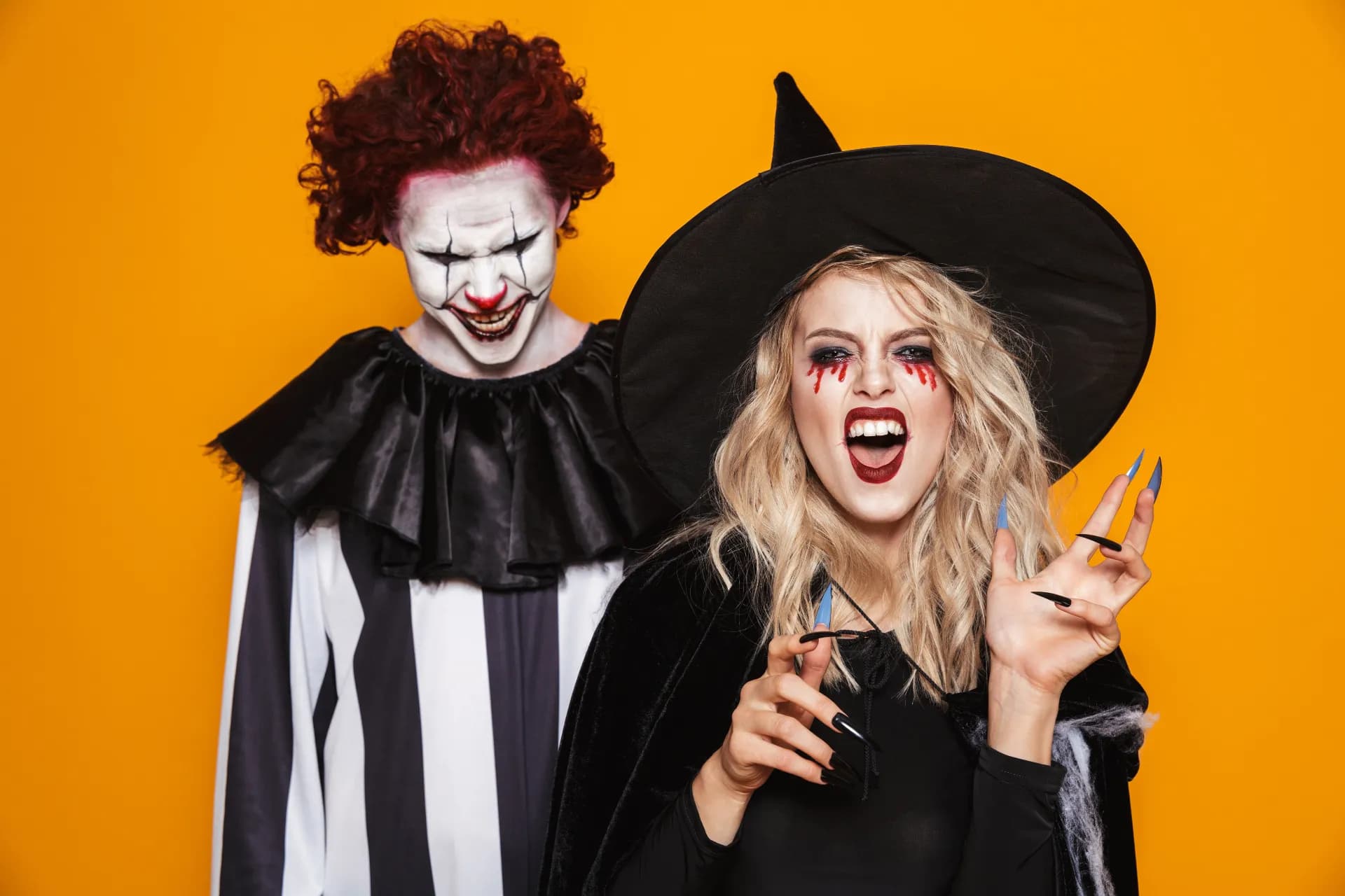 witch woman and joker man wearing black costume and halloween makeup