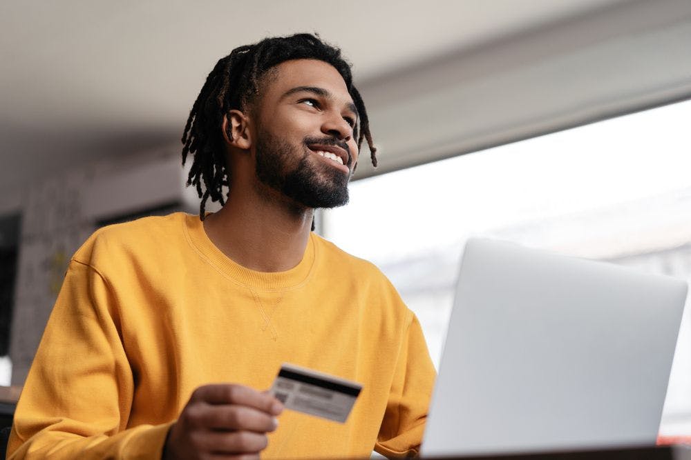 man-holding-credit-card-in-front-of-laptop